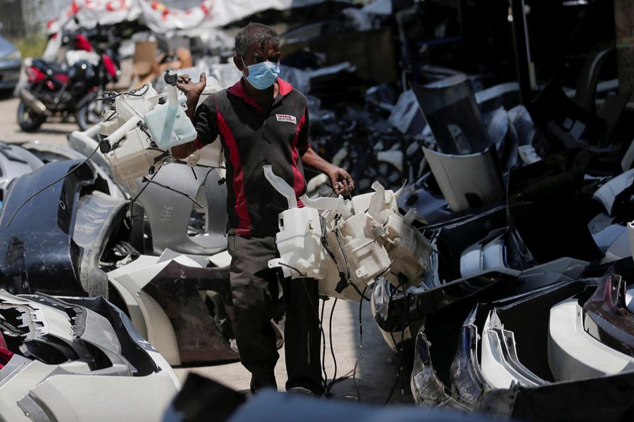 A worker carries used windscreen washer bottles at an area selling spare parts for cars, in a suburb town of Colombo, Sri Lanka on February 17, 2022 — Reuters photo