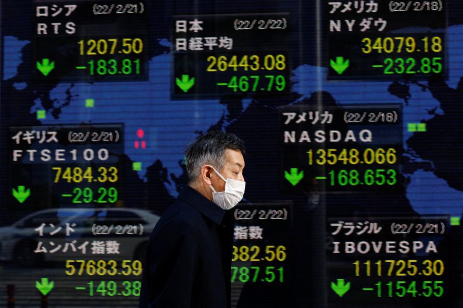 A man wearing a protective mask, amid the coronavirus disease (Covid-19) outbreak, walks past an electronic board displaying Japan's Nikkei index and various countries' stock market index prices outside a brokerage in Tokyo, Japan on February 22, 2022 — Reuters photo