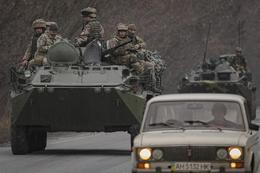 Ukrainian servicemen sit atop armored personnel carriers driving on a road in the Donetsk region, eastern Ukraine, Thursday, Feb. 24, 2022. Russian President Vladimir Putin on Thursday announced a military operation in Ukraine and warned other countries that any attempt to interfere with the Russian action would lead to "consequences you have never seen." (AP Photo/Vadim Ghirda)