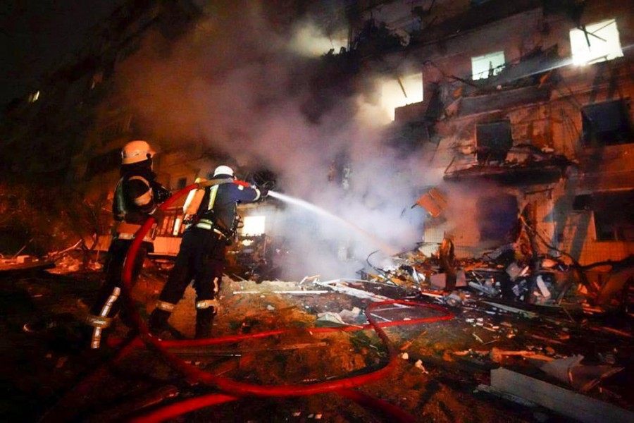 In this handout photo taken from video released by Ukrainian Police Department Press Service released on Friday, Feb. 25, 2022, firefighters hose down burning burning debris in front of a damaged building following a rocket attack on the city of Kyiv, Ukraine, Friday, Feb. 25, 2022.  (Ukrainian Police Department Press Service via AP)