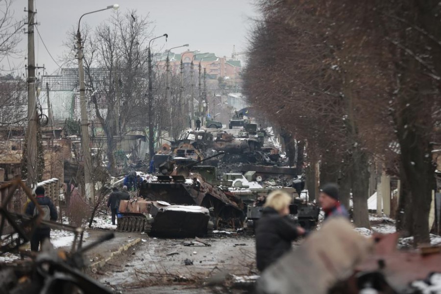 People look at the gutted remains of Russian military vehicles on a road in the town of Bucha, close to the capital Kyiv, Ukraine, Tuesday, March 1, 2022. (AP Photo/Serhii Nuzhnenko)