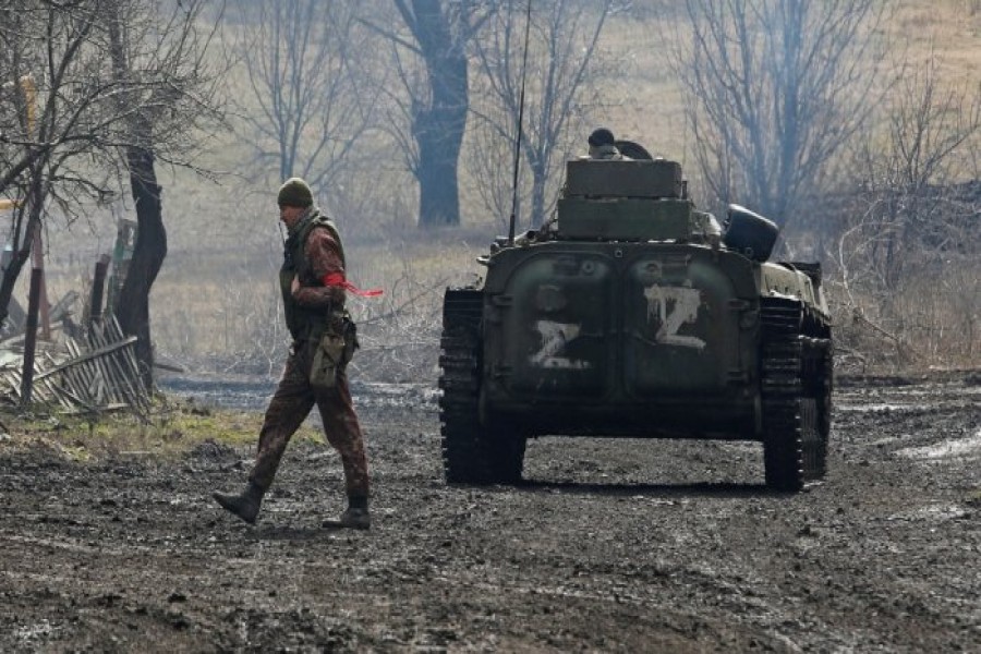 A service member of pro-Russian troops in a uniform without insignia walks next to an armoured vehicle in the Donetsk region. Credit: Reuters Photo