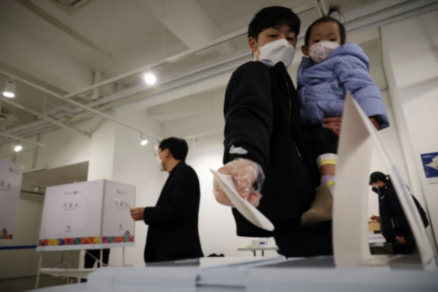 A man holding his child casts his vote at a polling station during the presidential elections in Seoul, South Korea, March 9, 2022. REUTERS/Kim Hong-Ji