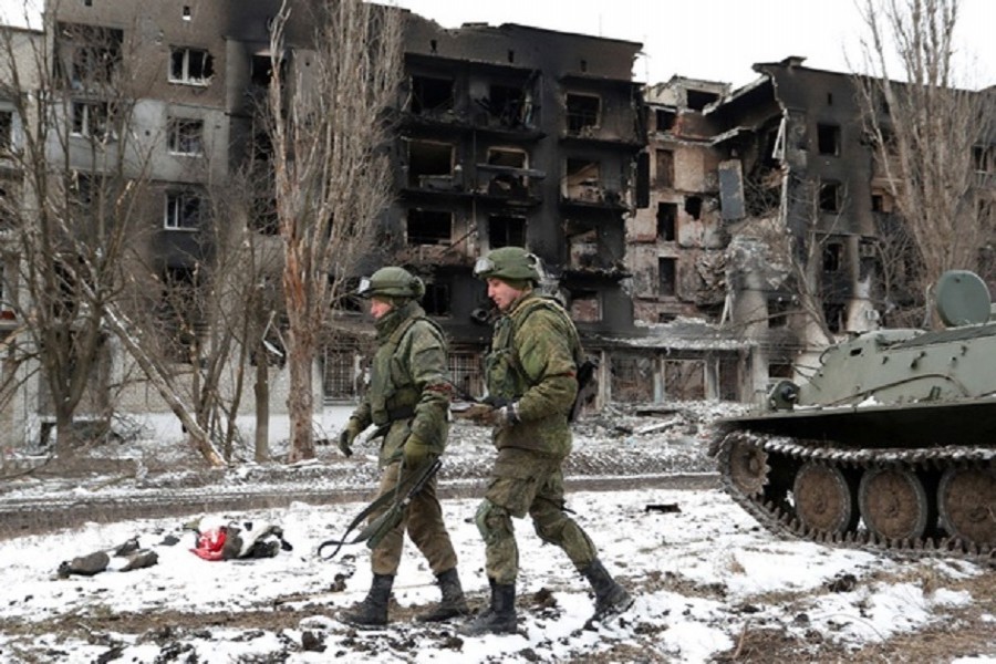 Service members of pro-Russian troops in uniforms without insignia walk near a residential building which was heavily damaged during Ukraine-Russia conflict in the separatist-controlled town of Volnovakha in the Donetsk region, Ukraine March 11, 2022. REUTERS/Alexander Ermochenko