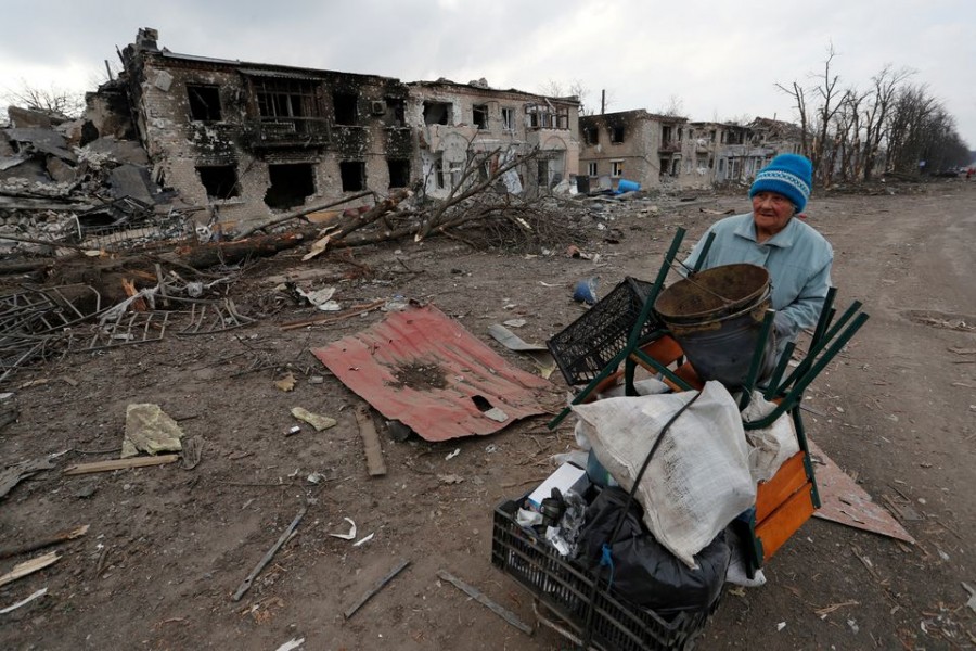 A woman pushes a trolley with her belongings along a street damaged during Ukraine-Russia conflict in the separatist-controlled town of Volnovakha in the Donetsk region, Ukraine March 15, 2022. REUTERS/Alexander Ermochenko/File Photo