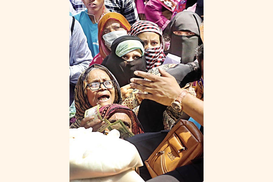 An elderly woman, tired and exhausted after waiting long hours in the queue under high temperature, desperately asks a staffer of a TCB sales point to provide essential commodities while others still wait there for their turn. The photo was taken from Segunbagicha in Dhaka on Sunday — FE photo by KAZ Sumon