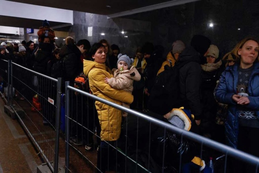 A woman holds a child as people fleeing Russia's invasion of Ukraine queue at the train station in Lviv, Ukraine March 21, 2022. Reuter