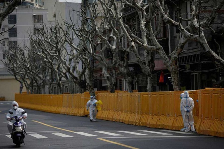 Staff in personal protective equipment (PPE) work by a barrier of an area under lockdown amid the coronavirus disease (COVID-19) pandemic, in Shanghai, China March 26, 2022. REUTERS/Aly Song