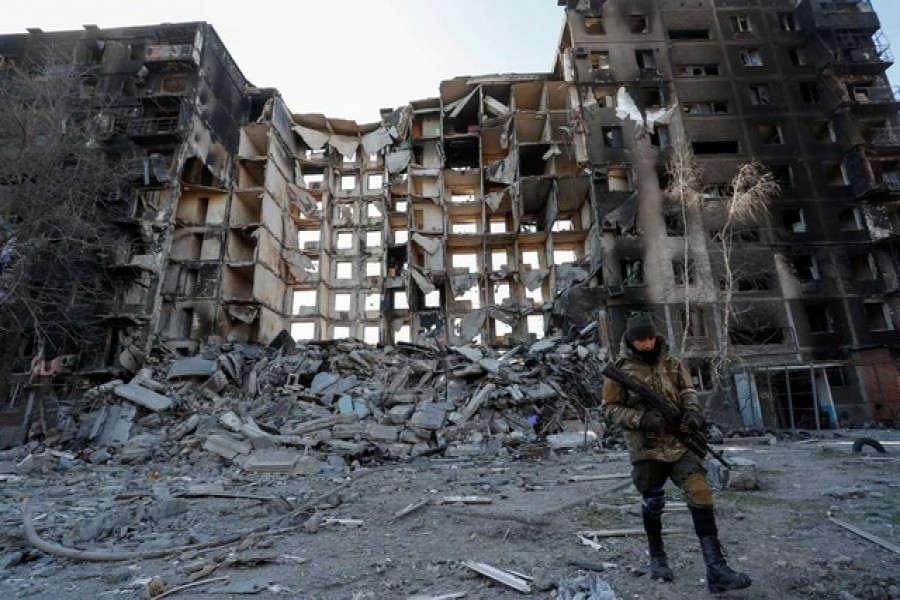 A service member of pro-Russian troops walks near an apartment building destroyed in the course of Ukraine-Russia conflict in the besieged southern port city of Mariupol, Ukraine March 28, 2022 -- Reuters