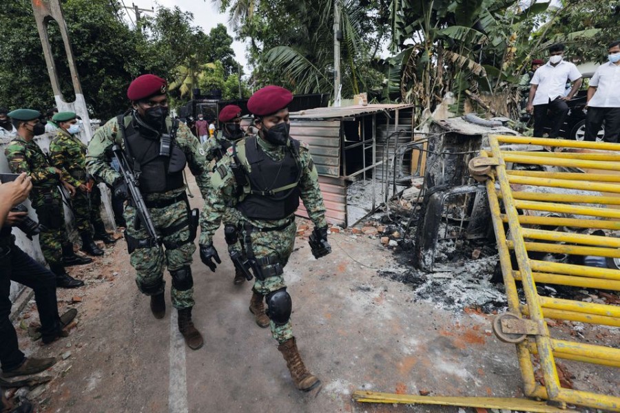 Sri Lankan army commandos walk past the damaged vehicles after they were set on fire by demonstrators at the top of the road to Sri Lankan President Gotabaya Rajapaksa's residence during a protest against him, as many parts of the crisis-hit country face up to 13 hours without electricity due to a shortage of foreign currency to import fuel, in Colombo, Sri Lanka April 1, 2022. REUTERS/Dinuka Liyanawatte