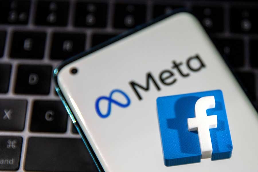 Woman holds smartphone with Meta logo in front of a displayed Facebook's new rebrand logo Meta in this illustration picture - Reuters