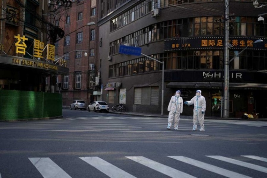 Workers in protective suits keep watch on a street during a lockdown, amid the coronavirus disease (COVID-19) pandemic, in Shanghai, China, April 16, 2022. Reuters