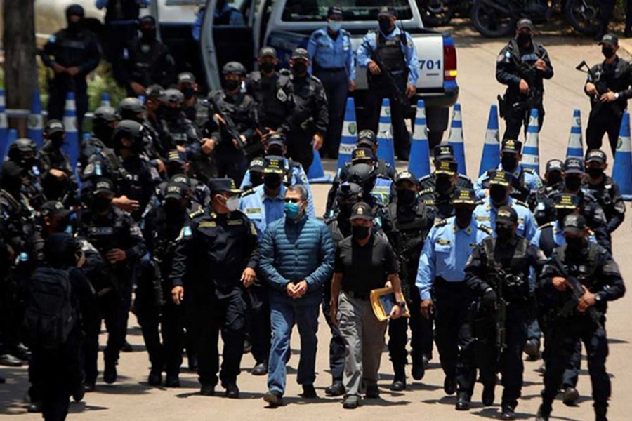Honduras former President Juan Orlando Hernandez is escorted by members of the National Police as they head towards a helicopter to transport him to the Hernan Acosta Mejia Air Force Base for his extradition to the United States, to face a trial on drug trafficking and arms possession charges, at a police base in Tegucigalpa, Honduras on April 21, 2022 — Reuters photo