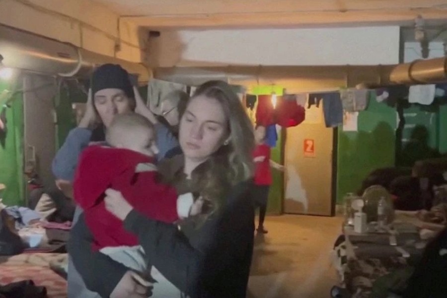 A woman holding a child walks past at as they take shelter amid Russia's invasion of Ukraine in a bunker said by Ukraine?s Azov Battalion to be in Azovstal steelworks in Mariupol, Ukraine in this screen grab taken from a handout video released on April 18, 2022. Video released on April 18, 2022. Azov Battalion/Handout via REUTERS