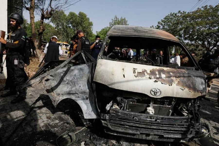 Police officers and members of the investigation team gather near a passenger van, after a blast at the entrance of the Confucius Institute University of Karachi, Pakistan April 26, 2022. REUTERS/Akhtar Soomro