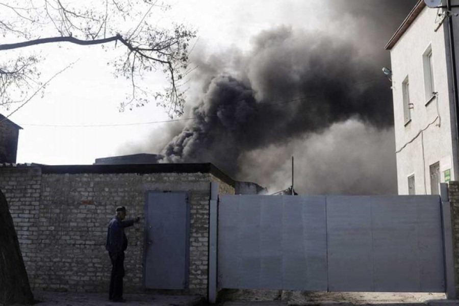 A person rings the bell outside a burning plant, following Russian shelling amid Russia's attack on Ukraine, in Kharkiv, Ukraine, April 30, 2022 – Reuters