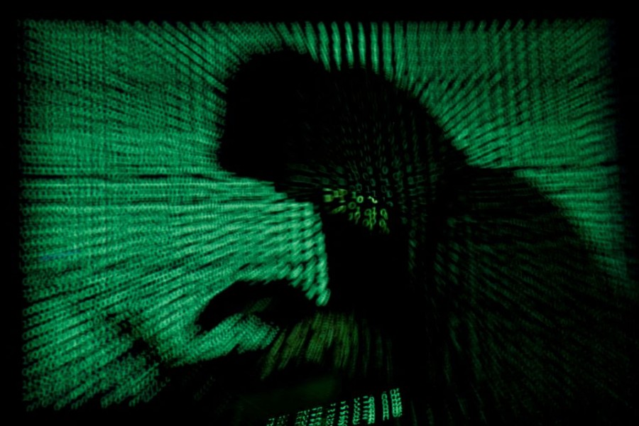 A hooded man holds a laptop computer as cyber code is projected on him in this illustration picture taken on May 13, 2017. REUTERS/Kacper Pempel/Illustration//File Photo