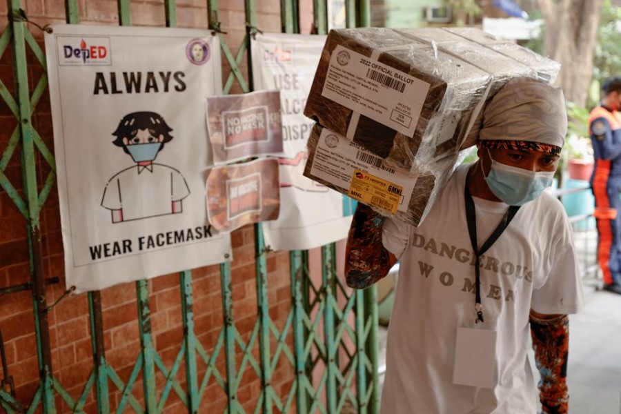 A worker carries ballot boxes as they arrive to an elementary school that is used as a polling precinct, a day prior to the national elections, in Manila, Philippines, May 8, 2022. REUTERS/Willy Kurniawan