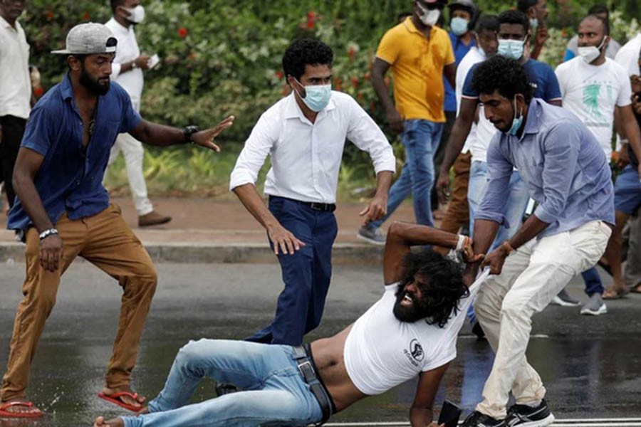 Supporter of Sri Lanka's ruling party tugs a member of anti-government demonstrator by his shirt during a clash between the two groups, amid the country's economic crisis in Colombo, Sri Lanka, April May 9, 2022. REUTERS/Dinuka Liyanawatte