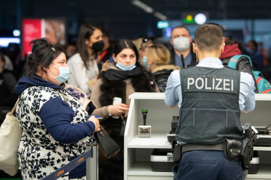 A German police officer checks the documents of Ukrainian refugees who arrived in Germany with a first refugee plane from Moldova, after fleeing from Russia's invasion of Ukraine, at the international airport of Frankfurt, Germany, March 25, 2022. Boris Roessler/Pool via REUTERS