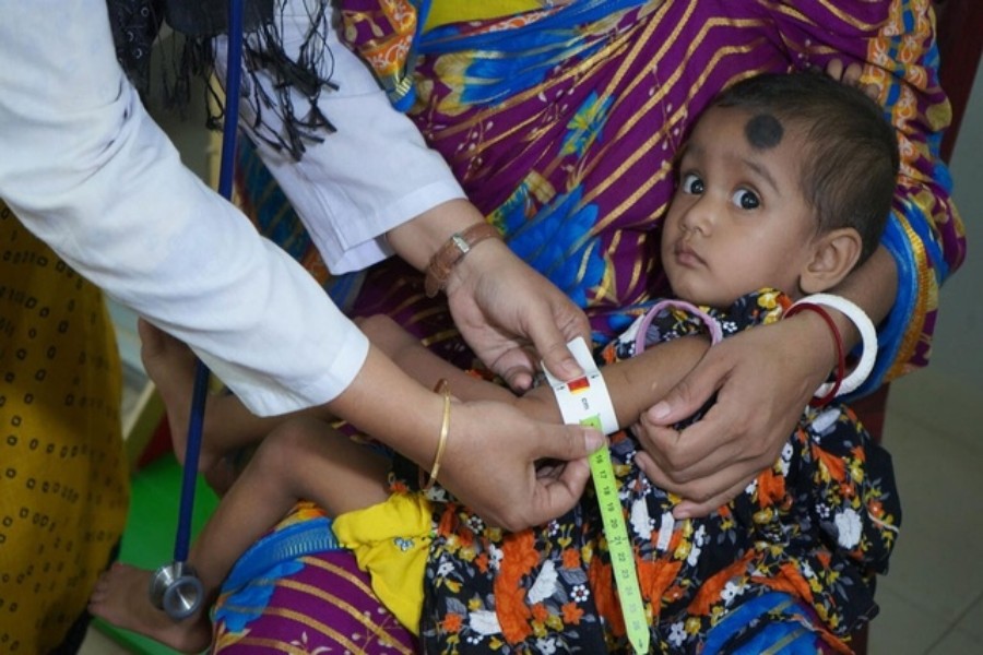 A doctor uses the mid-upper arm circumference measuring tape supplied by UNICEF to determine that 23-month-old Puja Rani has severe acute malnutrition. UNICEF/UN0481041/Shaon