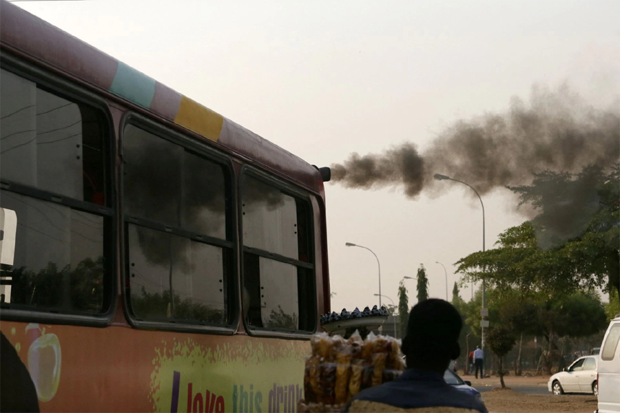 A man sells plantain chips near a bus with smoke seen from its exhaust at a bus park in Abuja, Nigeria on February 1, 2017 — Reuters/Files