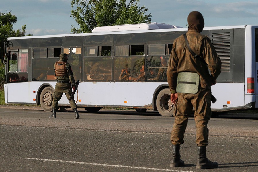 Service members of pro-Russian troops guard a road near a bus carrying Ukrainian soldiers, who surrendered at the besieged Azovstal steel mill in the course of Ukraine-Russia conflict, outside Mariupol, Ukraine on May 20, 2022 — Reuters photo