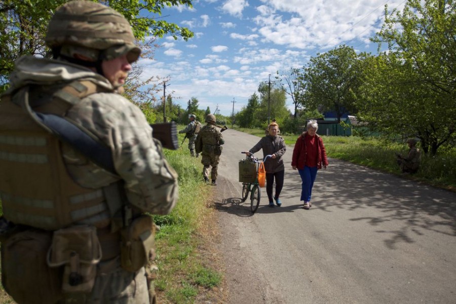 Local women walk along a street while Ukrainian servicemen patrol an area, as Russia's attack on Ukraine continues, in the town of Kurakhove, in Donetsk region, Ukraine May 20, 2022. Picture taken May 20, 2022. REUTERS/Anna Kudriavtseva