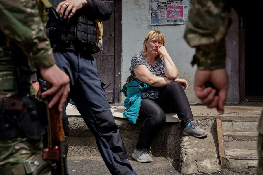 A local resident sits near her apartment building, as police officers stand, as Russia's attack on Ukraine continues, in Lysychansk, Luhansk region Ukraine on June 2, 2022 — Reuters photo