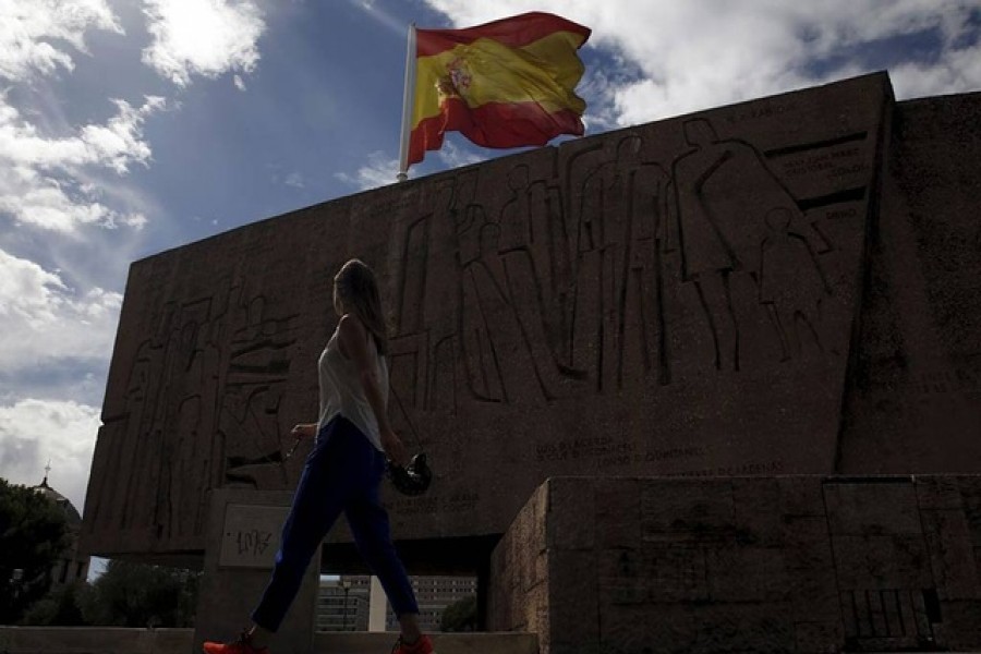 A woman walks past Discovery Monument as a huge Spanish flag flutters in Madrid, Spain, Aug 6, 2015. REUTERS/Sergio Perez