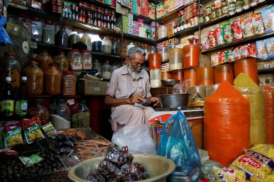 A shopkeeper uses a calculator while selling spices and grocery items along a shop in Karachi, Pakistan Jun 11, 2021. Reuters