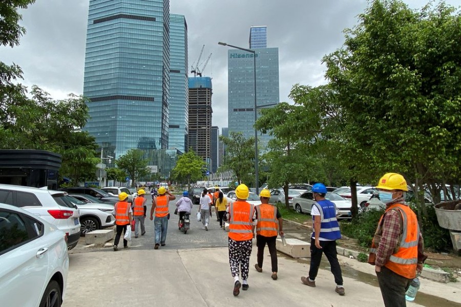 Construction workers walk past office buildings in Shenzhen's Nanshan district, Guangdong province, China June 10, 2022. REUTERS/David Kirton