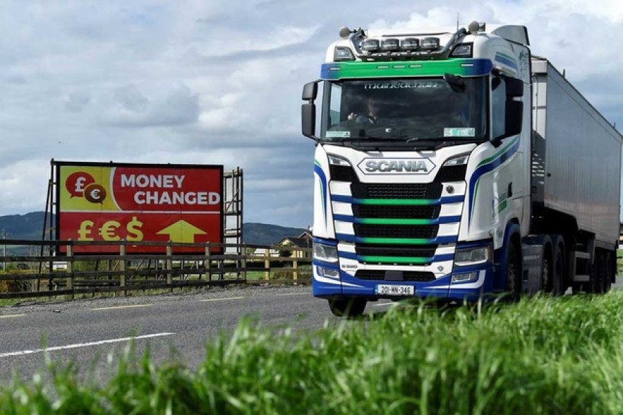 A truck drives past a 'money changed' sign for euro, sterling and dollar currencies on the border between Northern Ireland and Ireland, in Jonesborough, Northern Ireland, May 19, 2022. REUTERS