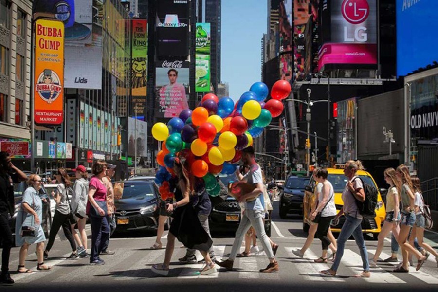 A woman carries a bunch of balloons through Times Square in New York, US, June 26, 2019. REUTERS