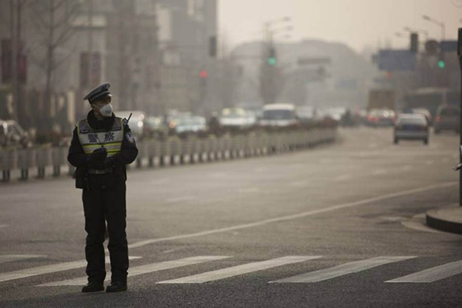 A policeman wearing a face mask stands on a road during a hazy day in Shanghai, Jan 20, 2014. REUTERS/Aly Song