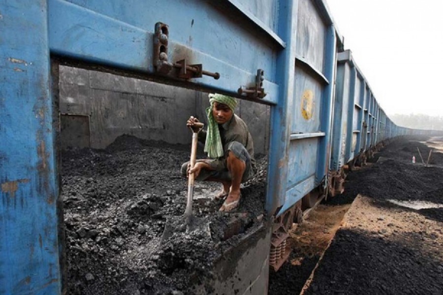 A worker unloads coal from a goods train at a railway yard in the northern Indian city of Chandigarh Jul 8, 2014. REUTERS/Ajay Verma/Files
