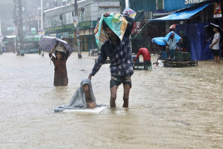 People wade through the water as they look for shelter during a flood, amidst heavy rains that caused widespread flooding in the northeastern part of the country, in Sylhet, Bangladesh, June 18, 2022. REUTERS/Abdul Goni