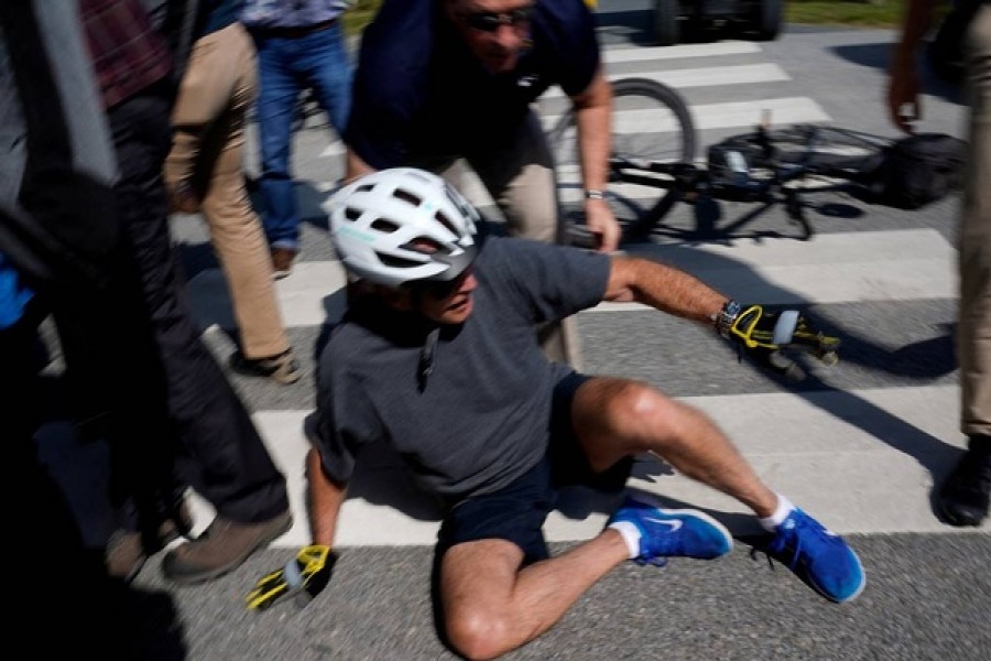 US President Joe Biden falls to the ground after riding up to members of the public during a bike ride in Rehoboth Beach, Delaware, US, June 18, 2022. REUTERS