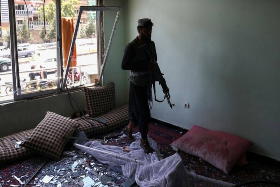 A Taliban fighter walks into a house damaged by the explosions, after an explosive-laden vehicle detonated amidst an attack on a Sikh temple in Kabul, Afghanistan, June 18, 2022. REUTERS/Ali Khara