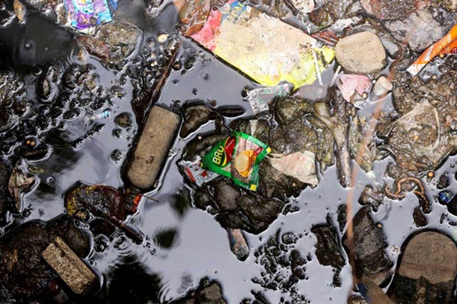 A plastic sachet of Bru coffee, a product of Hindustan Unilever Limited (HUL), is pictured among garbage inside an open sewer in Mumbai, India, May 10, 2022. Reuters