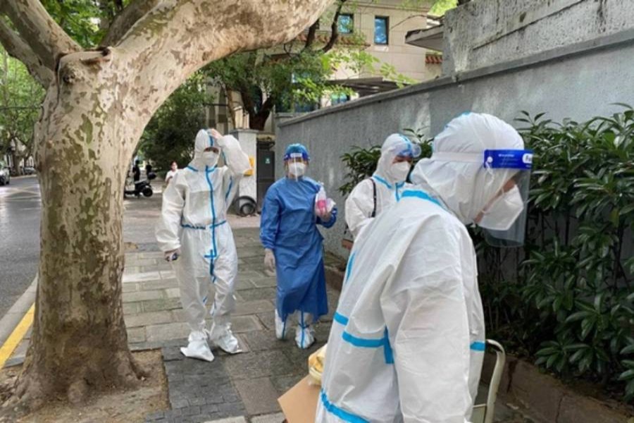 Workers in protective suits walk on a street, following the coronavirus disease (COVID-19) outbreak, in Shanghai, China June 9, 2022. (Reuters)