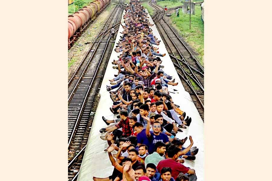 Defying risks, holidaymakers ride on the rooftop of a train to go to their village homes to celebrate Eid-ul-Azha with their near and dear ones. The photo was taken at Kamalapur Railway Station in Dhaka on July 8 this year —FE file photo