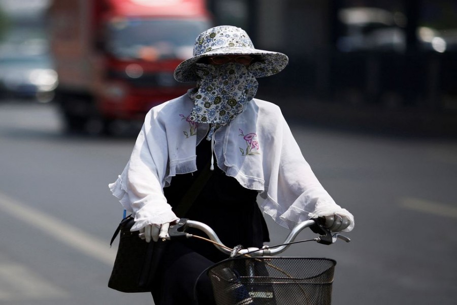 A woman covers herself with a hat and mask as she rides a bicycle in Beijing May 30, 2014. REUTERS/Kim Kyung-Hoon