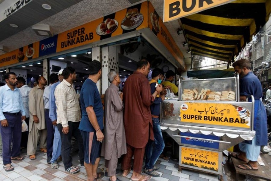 People wait for their turn to buy low-priced bun-kabab from a shop in Karachi, Pakistan June 10, 2022. Reuters