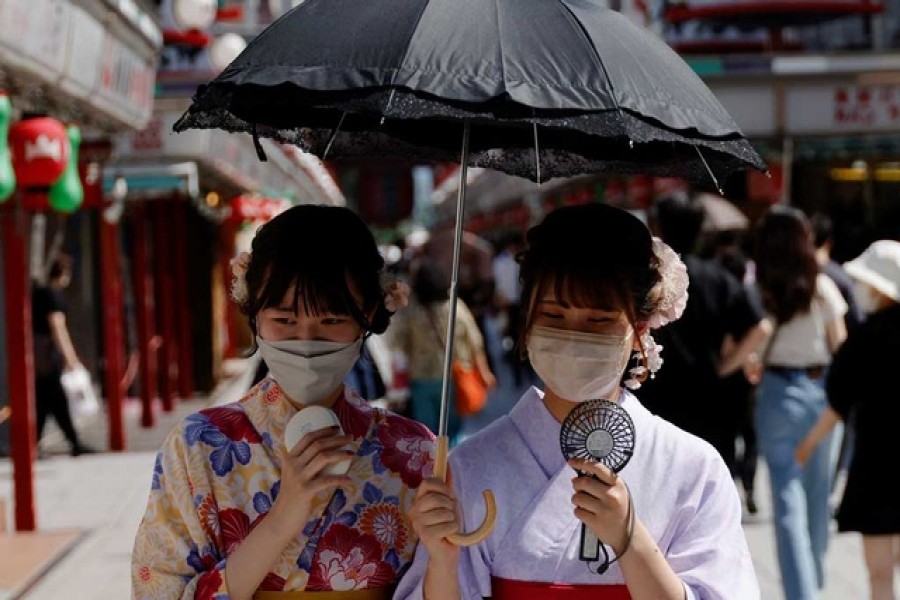 Women wearing summer kimonos use portable fans and an umbrella as they walk on the street as Japanese government issues warning over possible power crunch due to heatwave at Asakusa district in Tokyo, Japan Jun 29, 2022. Reuters
