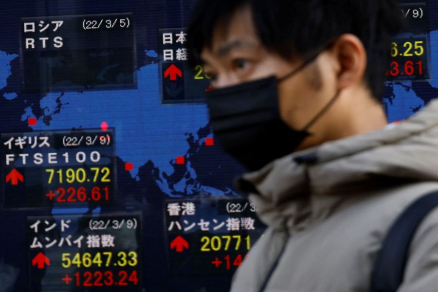A man wearing a protective mask, amid the coronavirus disease (COVID-19) outbreak, walks past an electronic board displaying various countries' stock indexes including Russian Trading System (RTS) Index which is empty, outside a brokerage in Tokyo, Japan, March 10, 2022. REUTERS/Kim Kyung-Hoon