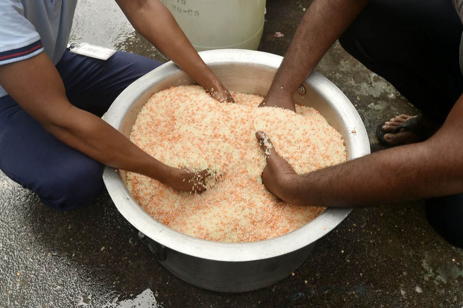Two young men mixing rice and lentils to prepare a meal in Dhaka. 	—Xinhua  Photo