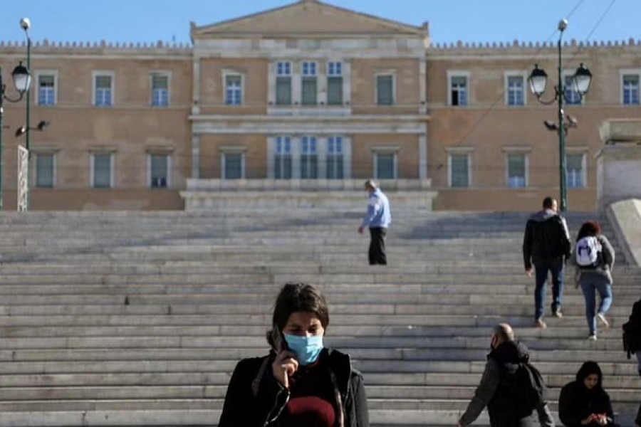 People wearing protective face masks make their way on Syntagma square after the Greek government imposed mandatory COVID vaccinations for people aged 60 and over, in Athens, Greece, December 1, 2021. REUTERS/Louiza Vradi