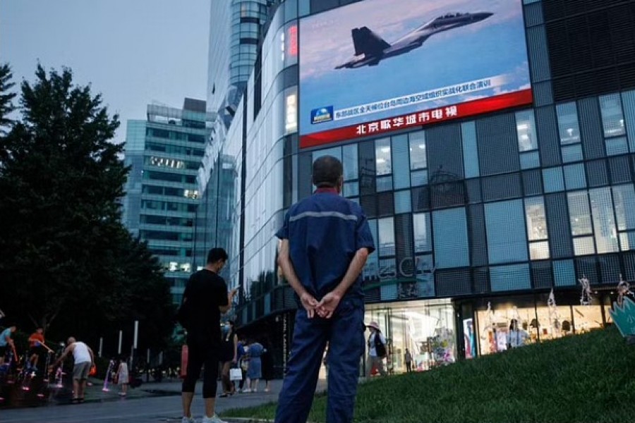 A man watches a CCTV news broadcast, showing a fighter jet during joint military operations near Taiwan by the Chinese People's Liberation Army's (PLA) Eastern Theatre Command, at a shopping centre in Beijing, China, August 3, 2022. REUTERS