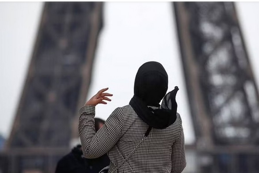 A woman wearing a hijab walks at Trocadero square near the Eiffel Tower in Paris, France, May 2, 2021.REUTERS/Gonzalo Fuentes/Files